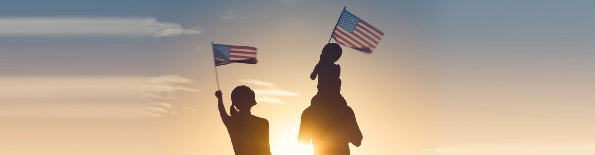 Patriotic silhouette of family waving American USA flags.